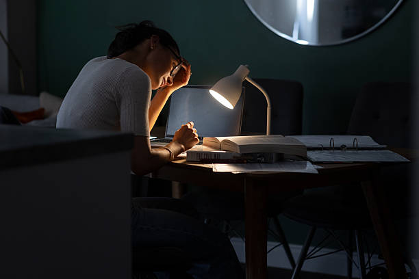 Student studying at night with a desk lamp